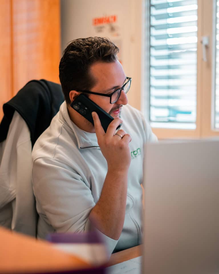 Mitarbeiter mit Brille telefoniert mit einem Kunden.