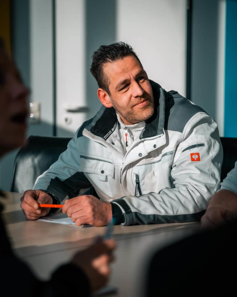 Mitarbeiter von Sitron in Arbeitskleidung am Besprechungstisch.